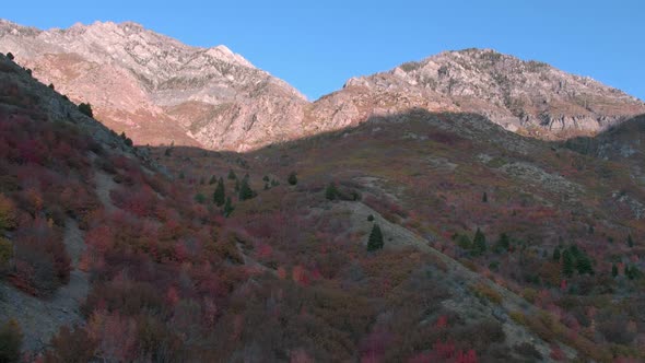 Flying up hill side towards mountain top lit up by the Sun alt