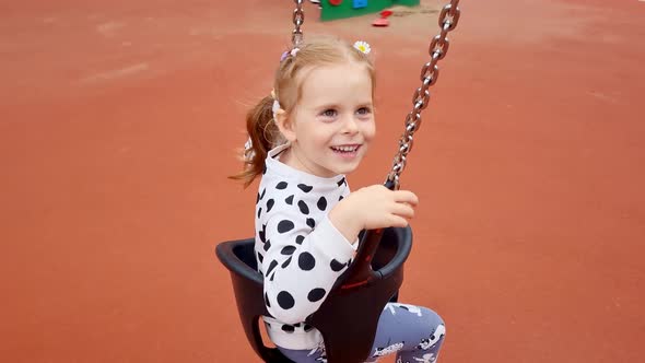 Happy Girl spinning on carousel at a colorful playground in summer day.