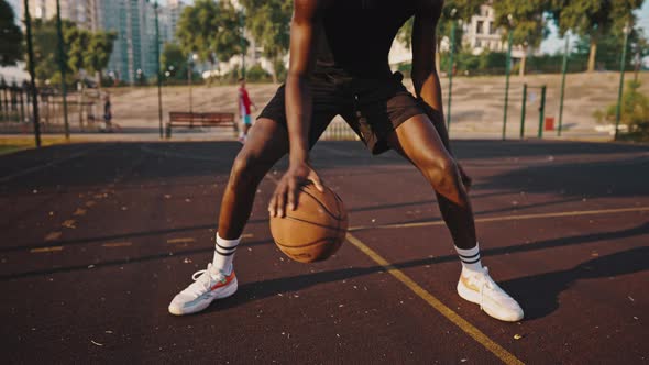 Closeup of a Young Black Basketball Player Dribbling the Ball Across the Field alt