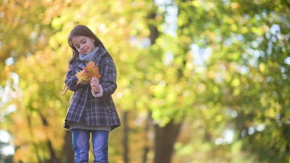 A cute girl in a coat walks through the autumn park