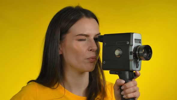 Darkhaired Woman Cinematographer is Using a Retro Camcorder for Shooting Video alt