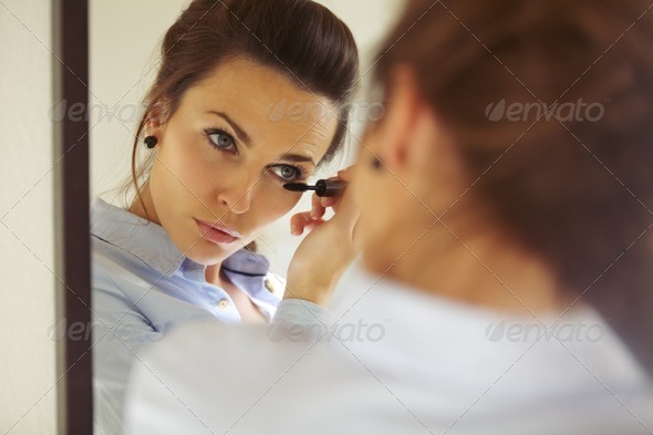 Businesswoman applying mascara