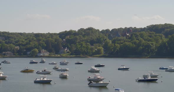 Aerial Pan of Boats Anchored on Harbor and Waterfront Houses Amongst Trees alt