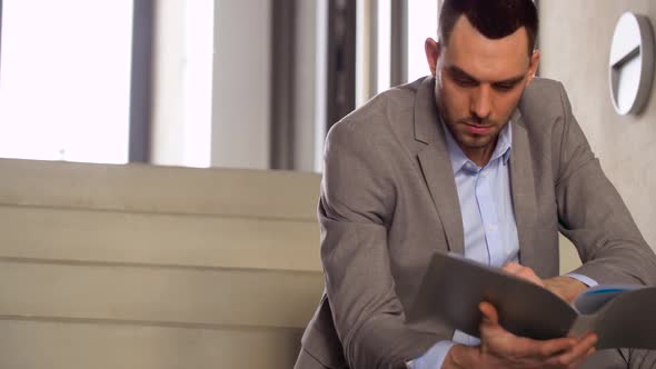 Businessman with Folder Sitting on Stairs alt
