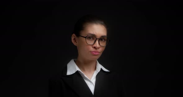 Business Woman with Glasses with a Dissatisfied Expression Looks at the Camera alt