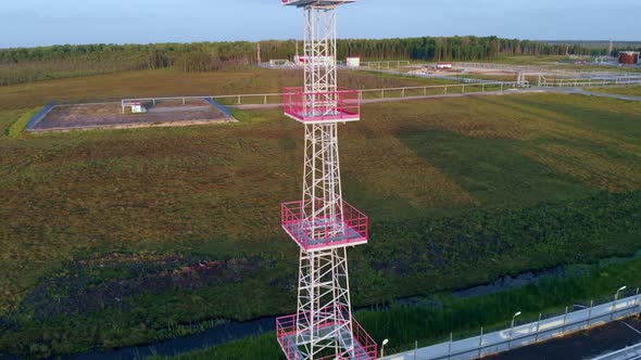 A Drone Rises Above a Metal Lighting Tower in an Oil and Gas Field alt