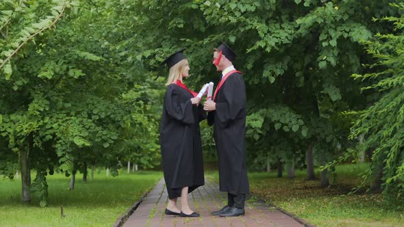 Windy Weather Pair of Graduates Standing in Park With Diplomas Wind of Change alt