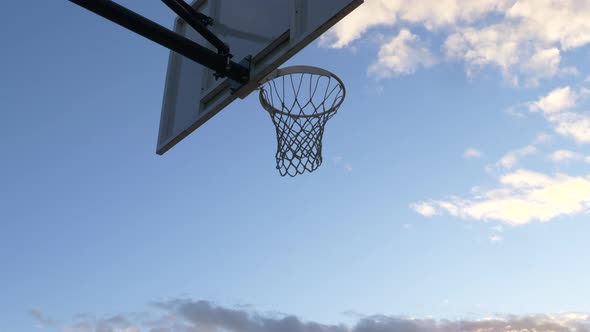 Low angle shot of Basketball falls through the net. View of a basketball hoop and net against the bl alt