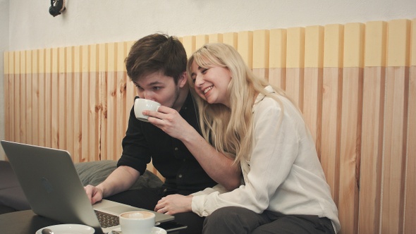 Couple of students having video chat with friends in coffee shop