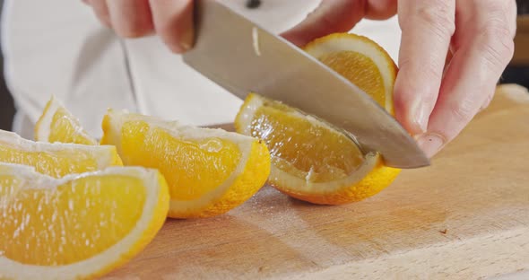 Close up of a chef knife peeling and slicing an orange alt