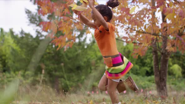 Young girl in Fall picking up and throwing leaves