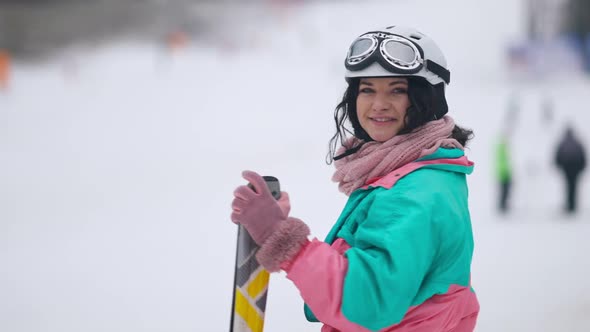 Back View of Slim Woman Standing on Snowy Slopes Turning to Camera Smiling alt