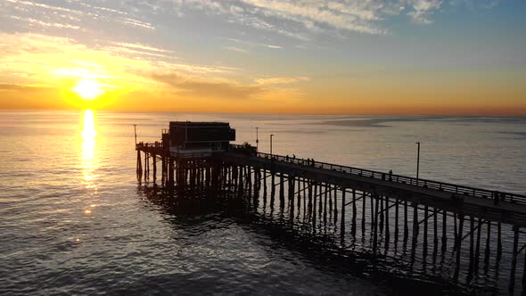 Drone footage over Newport beach pier with people in silhouette during a scenic southern California alt