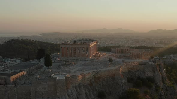 Aerial Flight Towards Acropolis of Athens with Greek Flag Waving in Beautiful Golden Hour Sunset alt