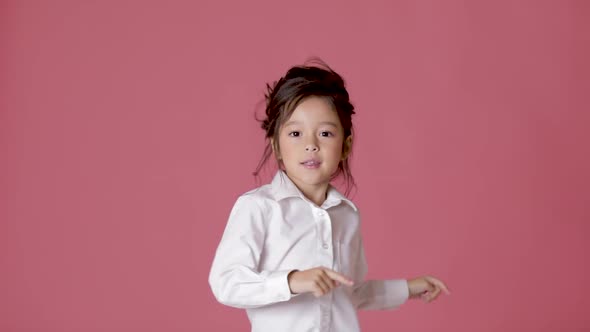 Little Child Girl in White Shirt Dancing on Pink Background