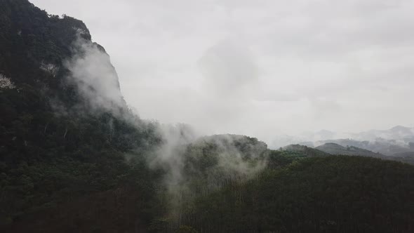 Flying Near the Mountains Above Tropical Rainforest with Mist Clouds on a Rainy Day