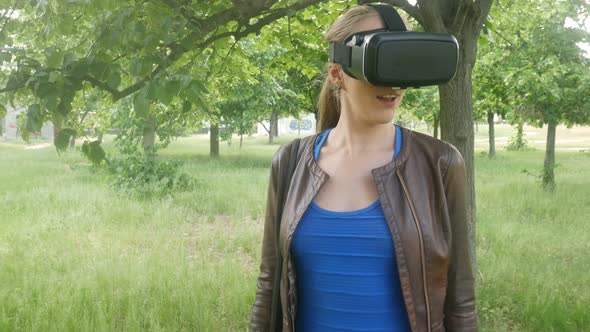 Sexy Cheerful Woman Uses a Modern Virtual Reality Helmet in the Nature