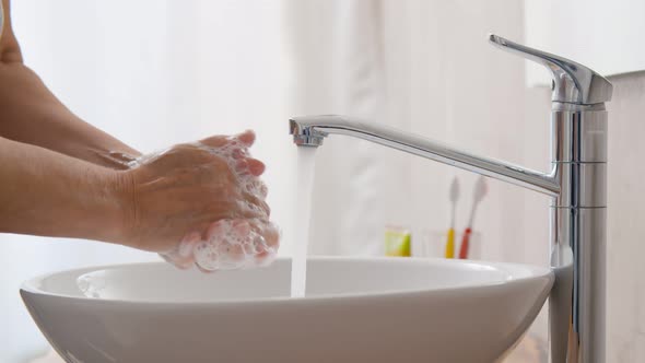 Close Up of Woman Washing Hands with Liquid Soap Over Sink in in Bathroom. alt