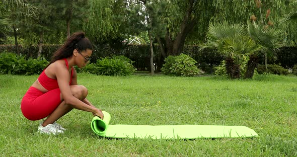 Black woman fold green yoga mat.