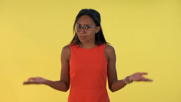 Mixedrace Young Woman Spreading Her Hands to the Sides and Saying What on Yellow Background alt
