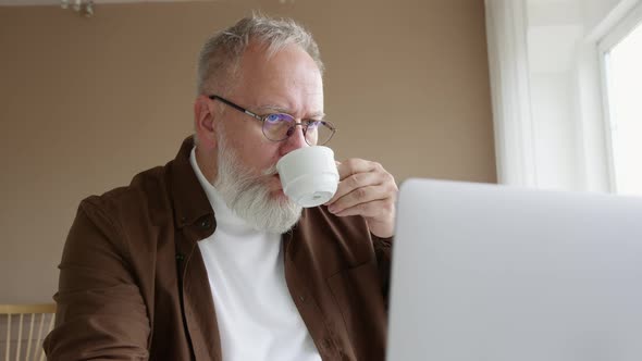 man with glasses works on a laptop at home