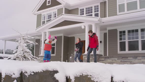 Three kids throwing snow by home in winter