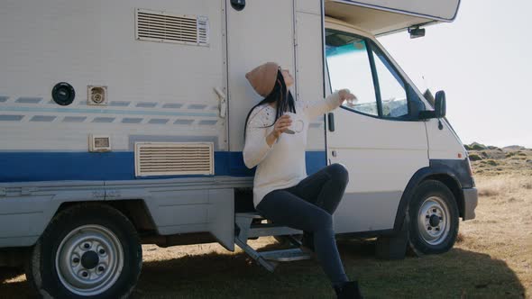 Young Woman Drinking Coffee and Sitting By Camper Car While Traveling Outdoors on Autumn Rbbro alt