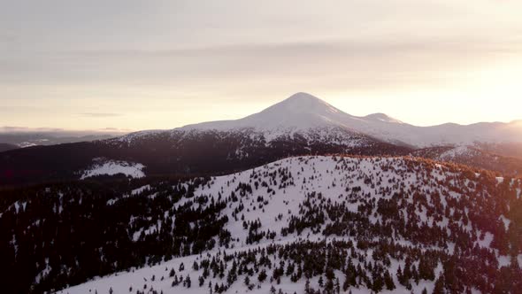 Drone Rising Above Forest Hill Revealing Mountain Top at Sunrise