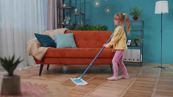 Funny Toddler Girl Kid Cleaning Washes Floors with a Mop at Home Dancing Singing in Positive Mood alt
