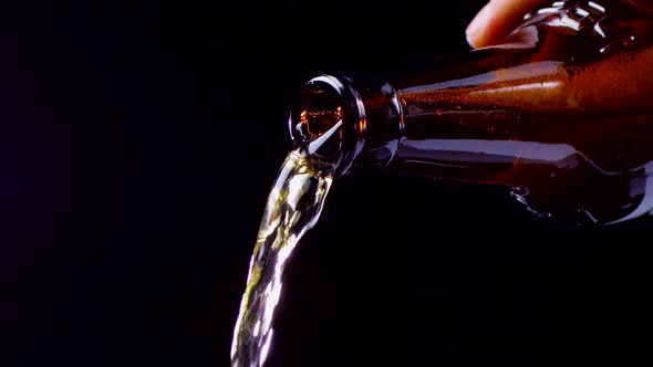 Slow Motion. Beer Is Poured From Dark Glass Bottle, Closeup alt