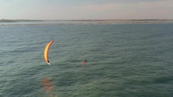 Aerial view of kitesurfer gliding and jumping across sea