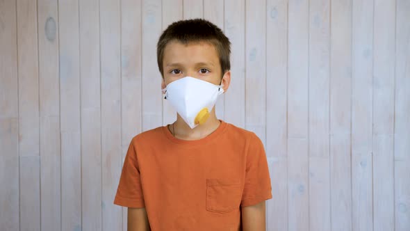 Portrait of Latin Boy in Respirator Over Light Gray Wall Background Looking at Viewer. Personal