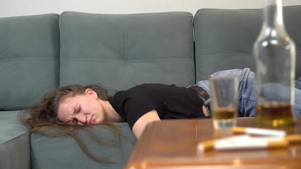 drunk woman after violent drinking session, with empty bottles, glasses alt
