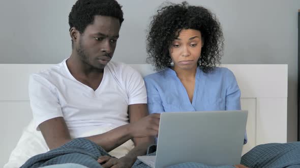 African Couple Using Laptop in Bed alt