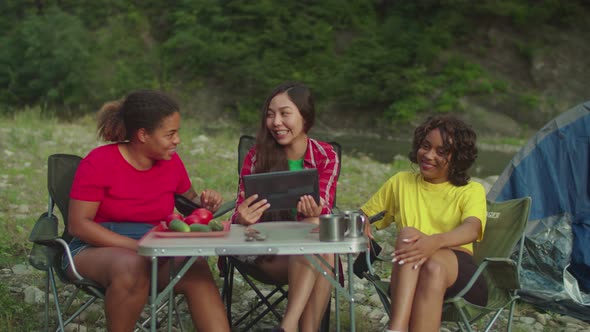 Pretty Multicultural Female Travelers with Tablet Pc Enjoying Leisure at Camping in Mountains alt