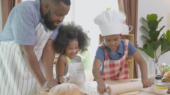 African American family with son and daughter rolling for thresh flour for cooking with father. alt