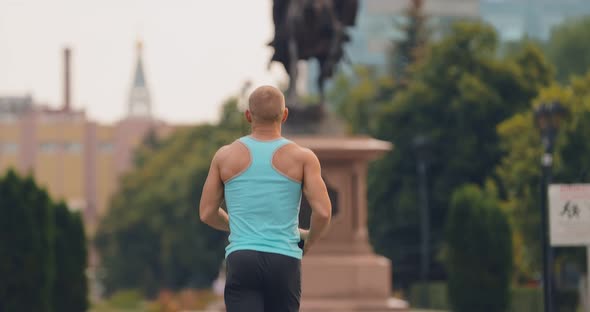 Inflated Male Athlete Runs Through the Park Jogging