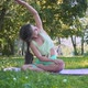 Young European Woman Sportswear Purple Mat Practicing Yoga Pose Park Green Lush Meadow City Park - VideoHive Item for Sale