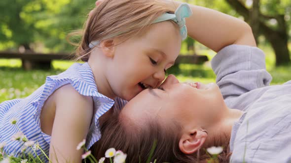 Happy Mother with Baby Girl Lying on Grass in Park alt