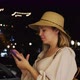 Handheld Shot of a Woman Using a Smartphone While Standing in the Middle of a Night City Street - VideoHive Item for Sale
