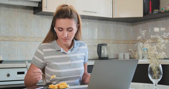 Serious Lady in Wireless Headphones Eats Cake and Types alt