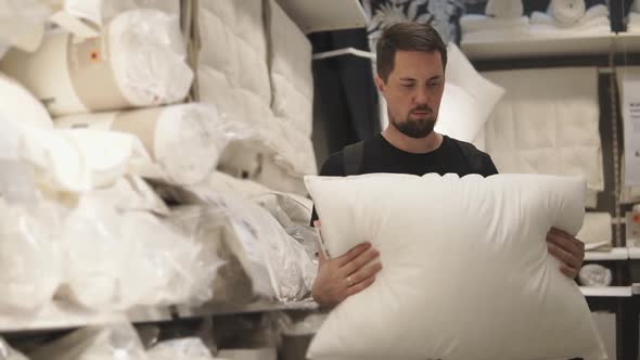 A Young Man Looks at the Pillow He Wants to Choose the Necessary Softness alt
