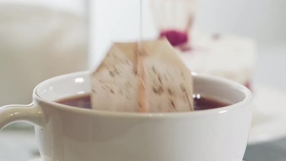 a tea bag is dipped into a mug of boiling water on the table. Brewing tea bags.