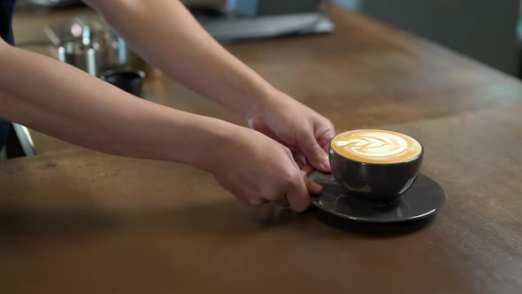 4K Asian man barista serving hot coffee with milk to customer on the counter alt