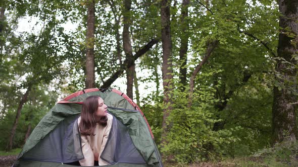 A Beautiful Woman Looks Out of the Tent and Looks Around in the Woods