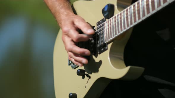 The young man plays the electric guitar  on the background of nature . close up.