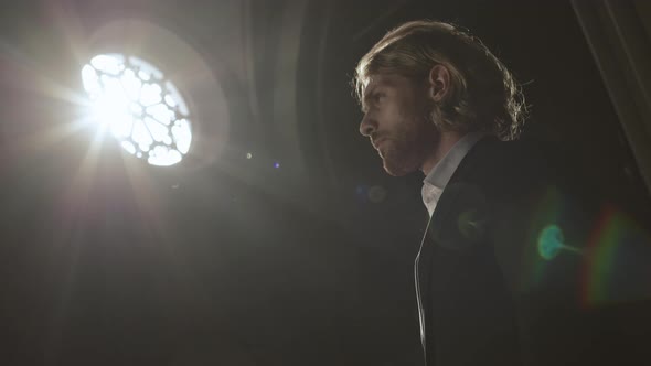 Young Handsome Caucasian Man Praying in Gothic Church alt
