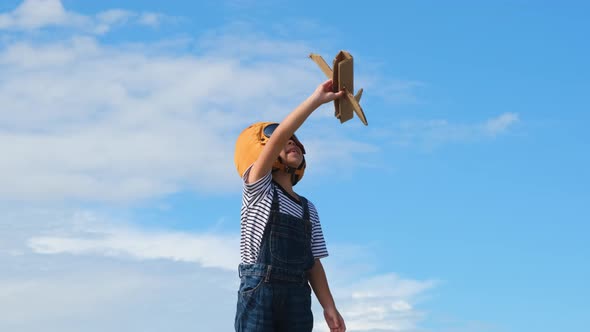 Cute dreamer little girl playing with cardboard planes in the meadow on a sunny day. alt