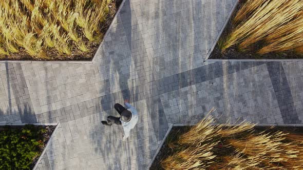 A Man is Actively Dancing Breakdancing Against the Background of Wheat and Street Gray Tiles alt