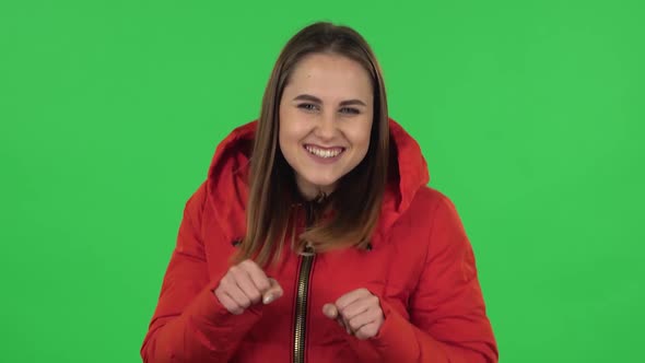 Portrait of Lovely Girl in a Red Down Jacket Is Dancing Funny. Green Screen alt